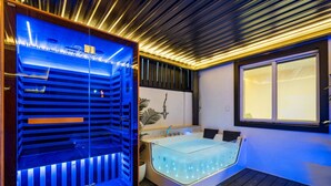 Un spa moderno con sauna de vidrio, una bañera grande con iluminación LED y suelo de madera.