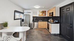 Una cocina moderna con comedor, que incluye una mesa y sillas blancas, un salpicadero de azulejos negros y armarios de madera.