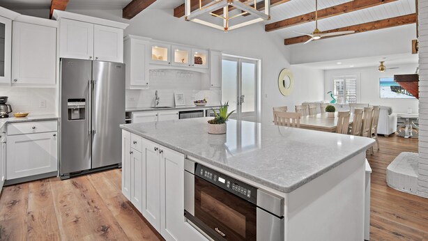 Una cocina amplia con armarios blancos, electrodomésticos de acero inoxidable y una isla grande.