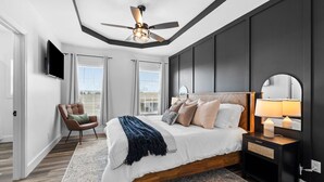 A modern bedroom with a large bed, a ceiling fan, a TV, and a view of the city. - 7 min to Wild Turkey and Four Roses - Sleeps 10 - Patio with Grill and View (Lawrenceburg)