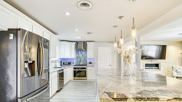 A modern kitchen with stainless steel appliances, a marble countertop, and a built-in oven. - Patio & Fenced Yard: Newly Renovated Hurst Home! (Hurst)