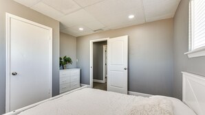 Une chambre à coucher avec un grand lit, une commode et une porte donnant sur une autre pièce.