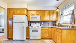 Una cocina con armarios de madera, un refrigerador blanco, un microondas, una estufa y un lavamanos.