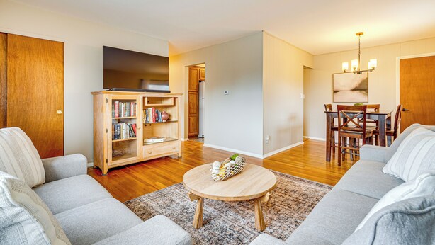 Una sala de estar con un sofá gris, una mesa de centro de madera y una estantería.