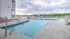 A swimming pool with a metal ladder, lounge chairs, and a stone feature. - 5th Fl Lakefront Condo: Elevator, Pool, Boat Slip! (Osage Beach)