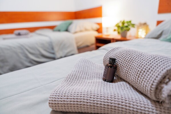 A neatly made bed with a rolled towel and a bottle of lotion.