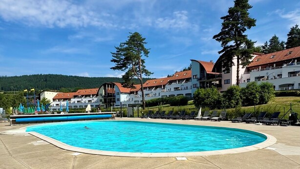 Una piscina con sillas de descanso y cielo despejado.