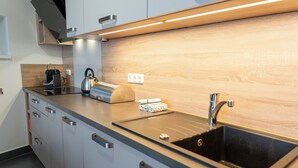 Una cocina moderna con un lavaplatos negro, electrodomésticos de acero inoxidable y armarios de madera.