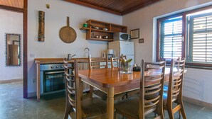 A compact kitchen with a wooden table and chairs, a built-in oven, and a microwave on a shelf.