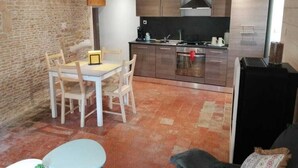 Un espacio habitable compacto con cocina, comedor y una pequeña zona de estar.