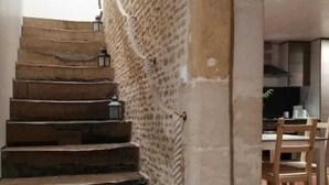 Una escalera con paredes de piedra y faroles, que lleva a una zona de cocina con muebles de madera.
