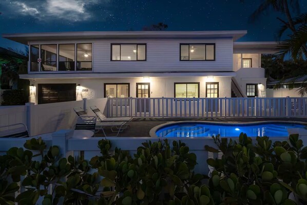A modern two-story house with a swimming pool, white exterior, and multiple windows.