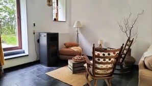 A cozy living room with a fireplace, a rocking chair, and a view of greenery outside. - Gîte de la Ferme du Semeur - Zaaiershof, Lessines. (Lessines)