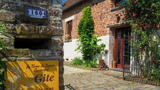 A cobblestone courtyard with a brick building, a sign for 'La Ferme du Semeur' and a '160 pub' sign. - Gîte de la Ferme du Semeur - Zaaiershof, Lessines. (Lessines)