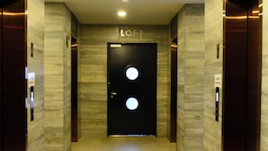 A modern hallway with a black door labeled "LOFT" and two elevators on either side. - Welcome to Ruelle505 (Tijuana)