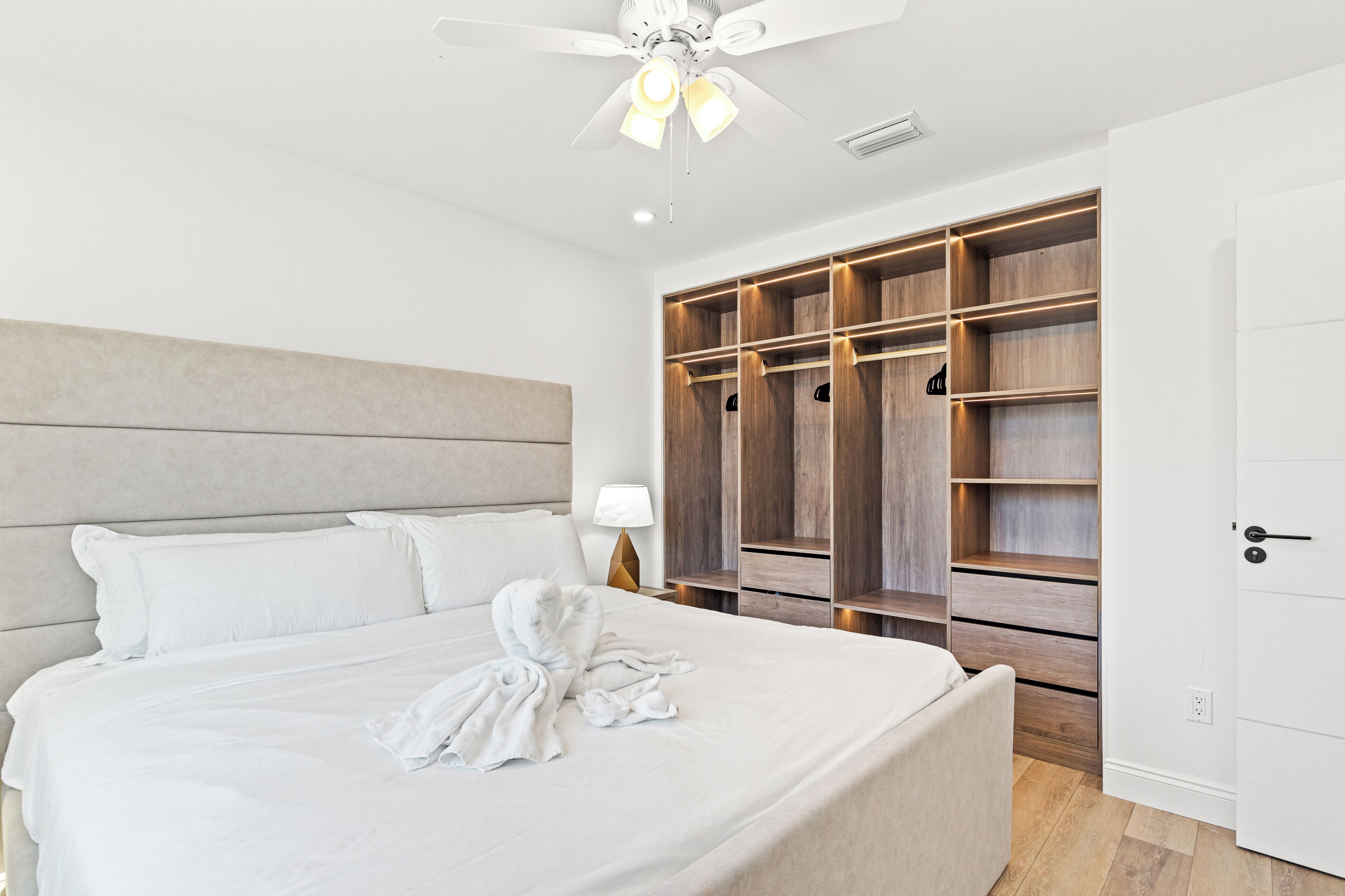 A hotel room with a large bed, a ceiling fan, and a walk-in closet with multiple shelves.