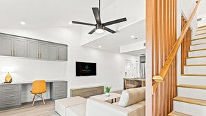 A modern living room with a sofa, a dining area with a wooden table, and a kitchen with grey cabinets. - Ocean Breeze (Panama City Beach)