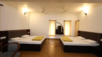 A hotel room with two single beds, wooden flooring, ceiling fans, and a mirror above the beds.