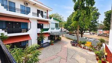Un edificio de varios pisos con balcones, un patio empedrado y plantas en macetas.