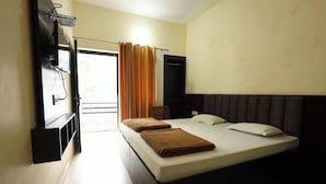 Ein Hotelzimmer mit Bett, Stuhl, Fernseher und einem fenster mit Vorhängen.