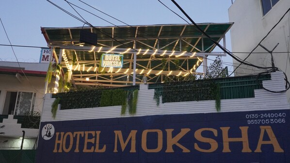 Un edificio con un letrero que dice 'HOTEL MOKSHA' y un letrero de neón encima.