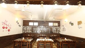Ein Restaurant mit Holztischen und -stühlen, einem gemusterten Boden und dekorativer Wandkunst.