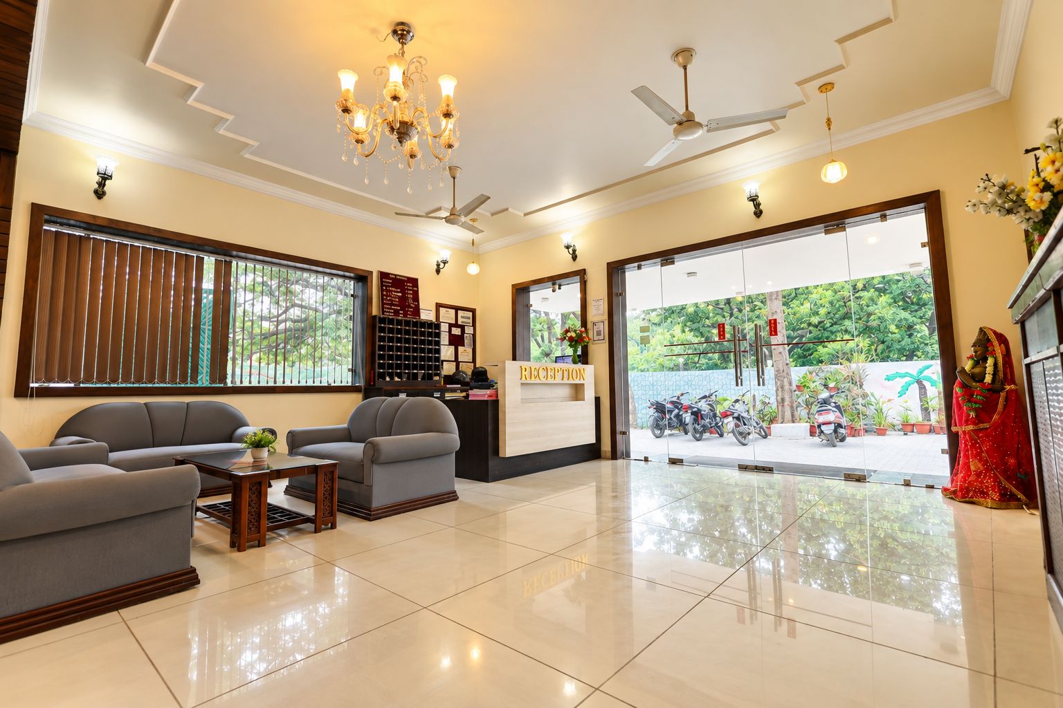 A reception area with a reception desk, seating, a chandelier, ceiling fans, and a view of the outside.
