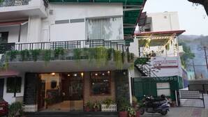 Ein Gebäude mit Balkon, Blumentöpfen, einem Schild für eine Meditations- und Klanganwendungsakademie und einem abgestellten Motorrad.