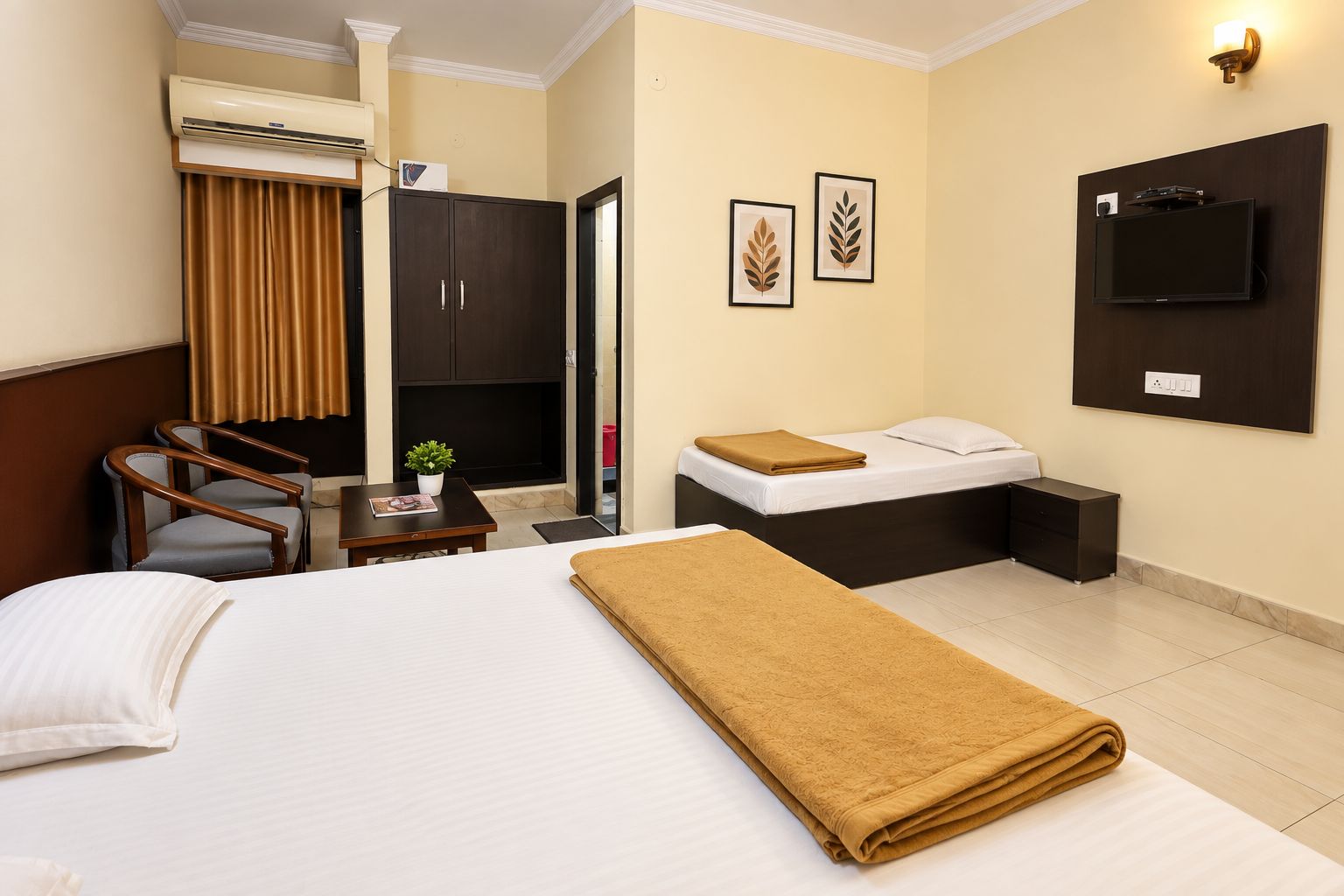 Habitación de hotel con cama, escritorio, silla, armario, televisor y una obra de arte en la pared.