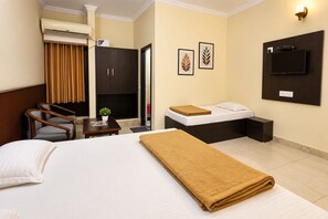 Ein Hotelzimmer mit Bett, Schreibtisch, Stuhl, Kleiderschrank, Fernseher und einem Bild an der Wand.