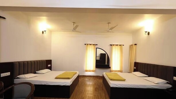 Ein Hotelzimmer mit zwei Betten, Holzboden, einem Sessel und einem Deckenventilator.
