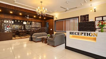 A reception area with a reception desk, seating, a chandelier, and a view of the hotel interior.