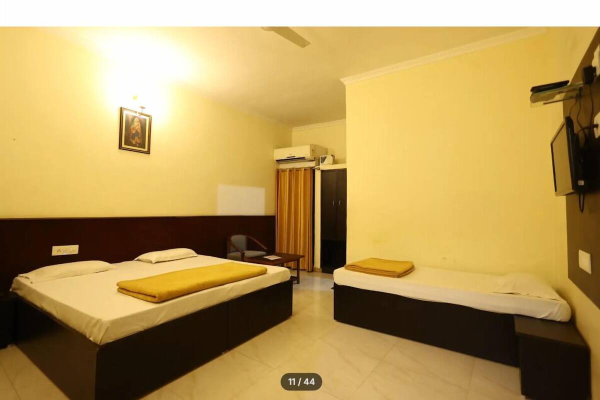 A hotel room with two beds, a desk, a chair, a wardrobe, and a television mounted on the wall.