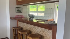 Een keuken met een houten aanrechtblad, een geweven rugleuning en drie bamboestoelen.