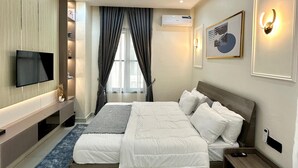 Ein modernes Hotelzimmer mit einem großen Bett, einem Flachbildfernseher, einer Klimaanlage und einem gerahmten Kunstwerk an der Wand.