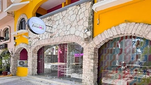 A building with a stone facade, yellow walls, and a sign for 'hostales casa M'. - Hostal CASA MX quinta avenida (Playa del Carmen)