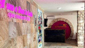 A hotel lobby with a neon sign, a stone wall, and a red archway. - Hostal CASA MX quinta avenida (Playa del Carmen)