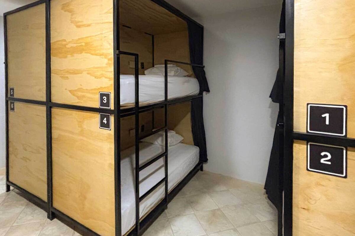 Una stanza in stile dormitorio con letti a castello, divisori numerati e pavimento piastrellato.