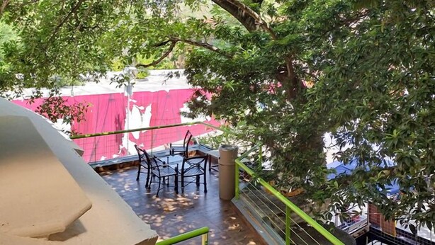 A covered outdoor seating area with tables and chairs, surrounded by trees. - Hostal CASA MX quinta avenida (Playa del Carmen)