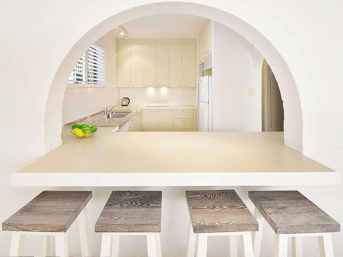 Une cuisine moderne avec une arche, un îlot central et des tabourets de bar.