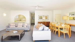 Uma sala de estar moderna com sofá, mesa de centro e área de jantar com cadeiras e mesa.