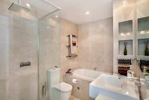 A modern bathroom with a glass shower enclosure, a bathtub, and a toilet.