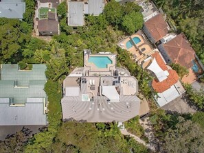An aerial view of a residential area with multiple buildings, a swimming pool, and surrounding greenery.