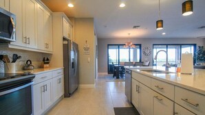 A modern kitchen with white cabinets, stainless steel appliances, and a large island. - Impeccable 3 BR / 2 BA home with expansive lake view - Serenity Garden (Venice)