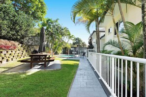 Área de pátio com piscina, móveis de exterior e cerca branca.