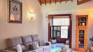 Sala de estar com teto de madeira alto, um sofá, uma mesa de centro e uma porta com janela.