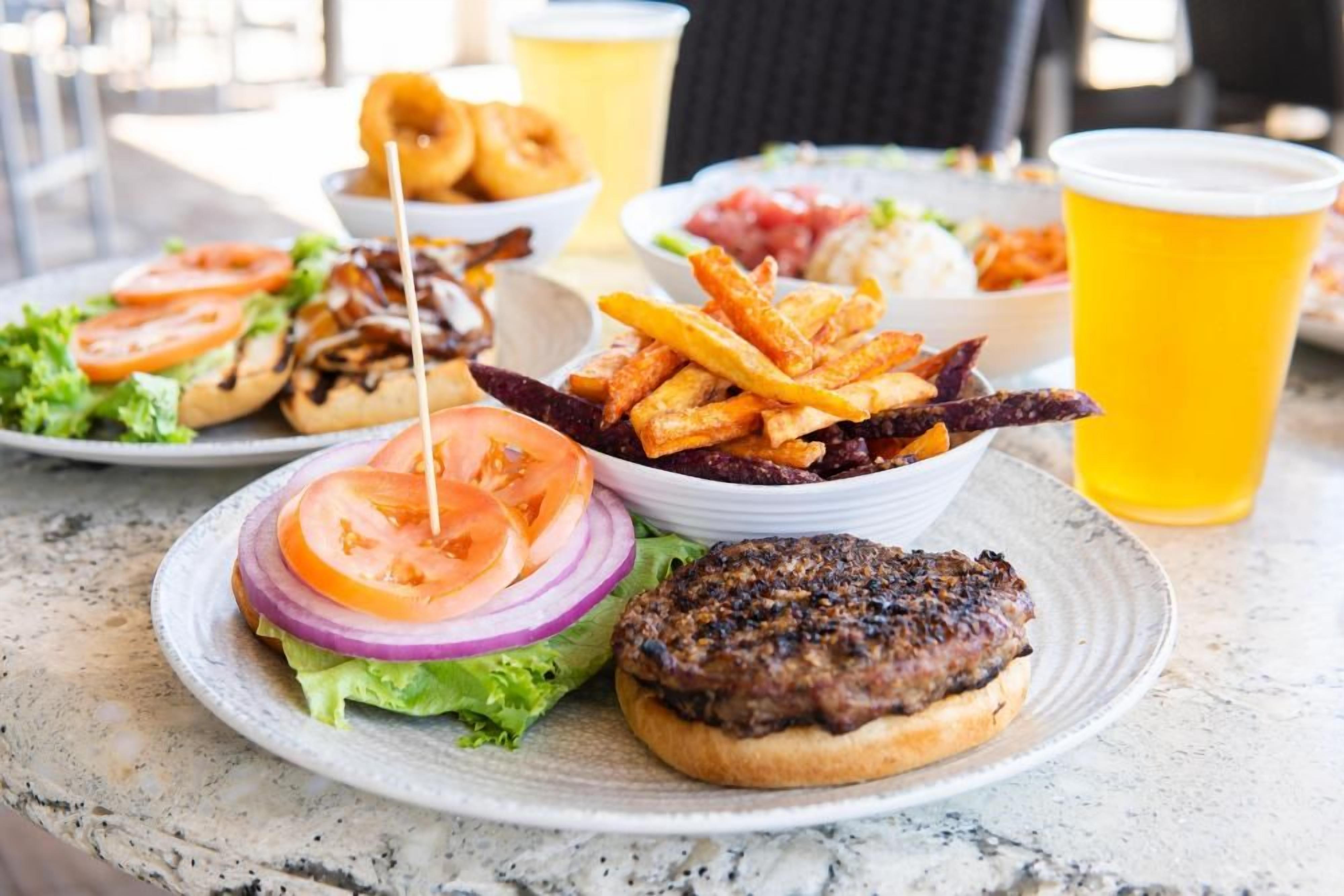 A meal with a burger, fries, and onion rings on a table.
