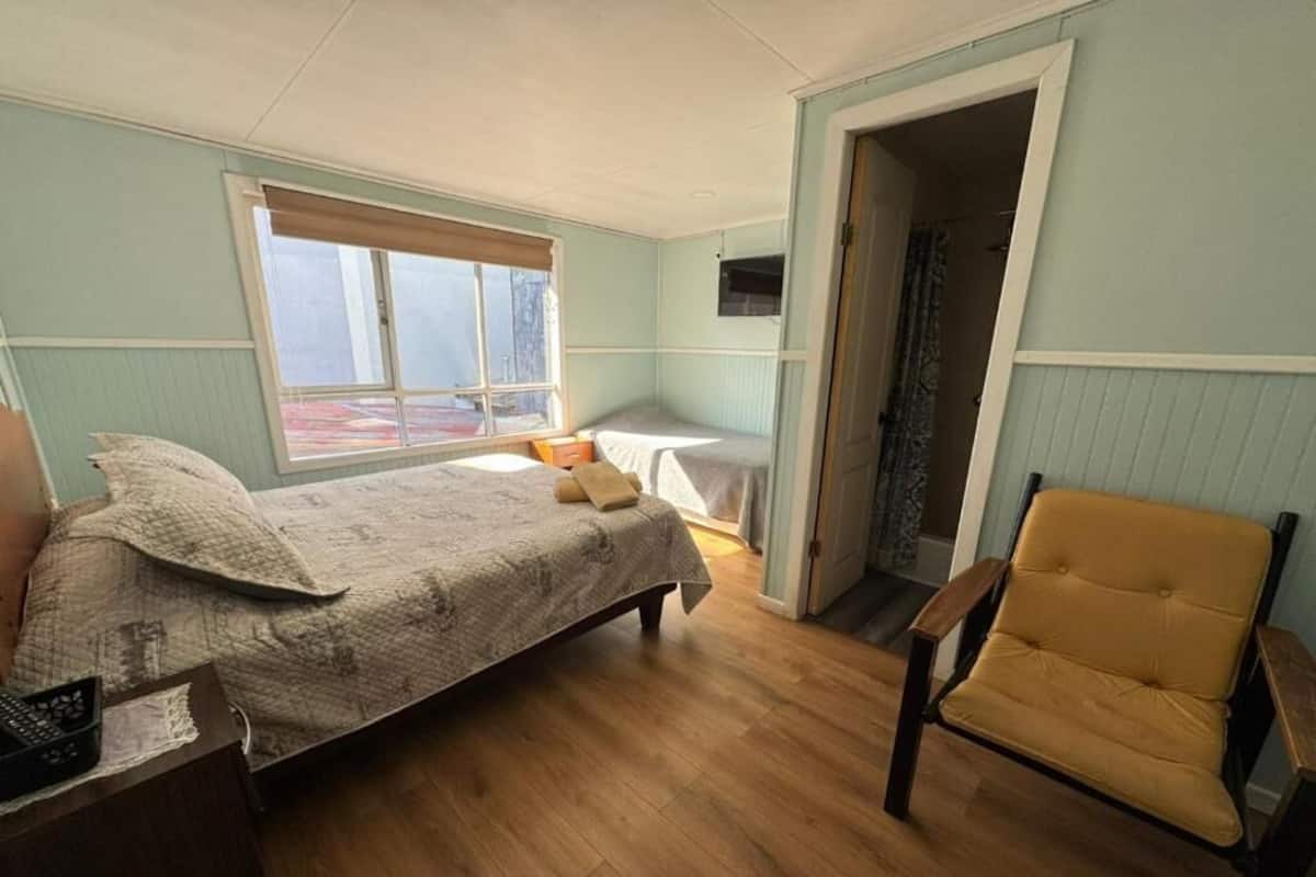 Une chambre à coucher avec un lit, une chaise, un bureau et une fenêtre.