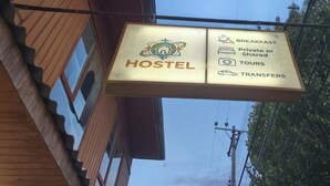 A hostel sign with amenities including breakfast, private or shared rooms, tours, and transfers.