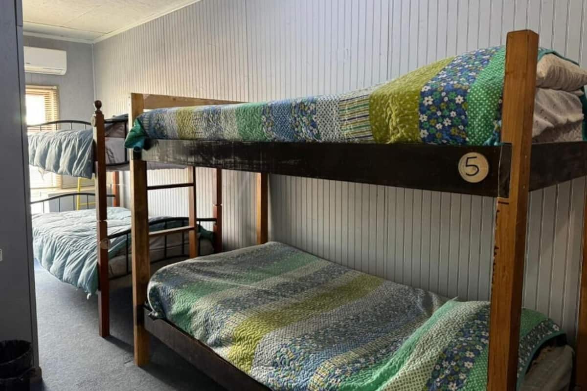 Une chambre avec un lit superposé, une couverture à rayures, une structure de lit superposé en bois et le chiffre « 5 » sur le côté.